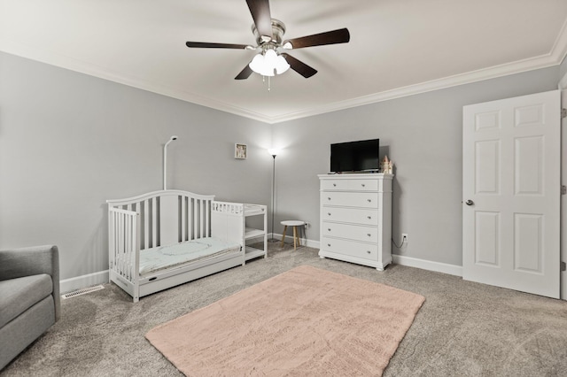 carpeted bedroom featuring crown molding, ceiling fan, and a crib