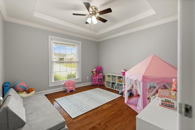 bedroom with dark wood-type flooring, ceiling fan, a raised ceiling, and crown molding