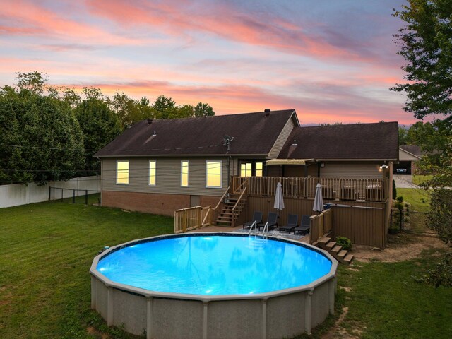 pool at dusk with a yard and a deck