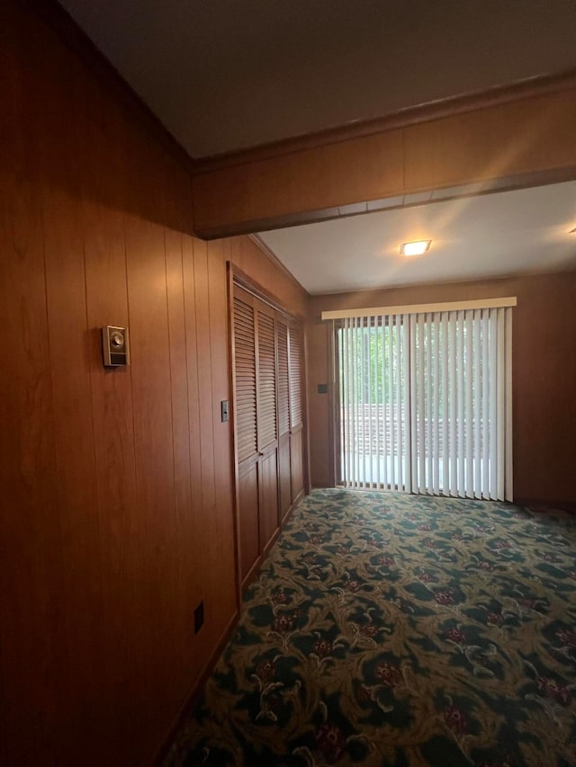 corridor with ornamental molding, wooden walls, and carpet flooring