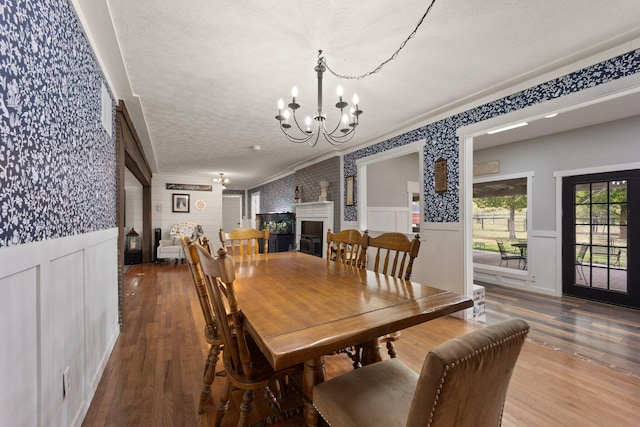 dining room with wood-type flooring, a fireplace, a chandelier, and ornamental molding