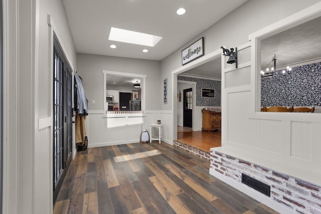 mudroom featuring ornamental molding, dark hardwood / wood-style floors, an inviting chandelier, and a skylight