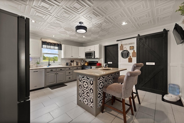 kitchen featuring gray cabinets, stainless steel appliances, a barn door, sink, and white cabinets