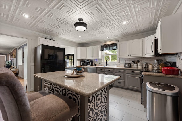 kitchen with white cabinetry, a kitchen island, sink, and light stone countertops