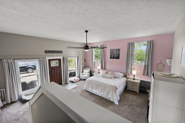 carpeted bedroom featuring multiple windows, ceiling fan, and a textured ceiling