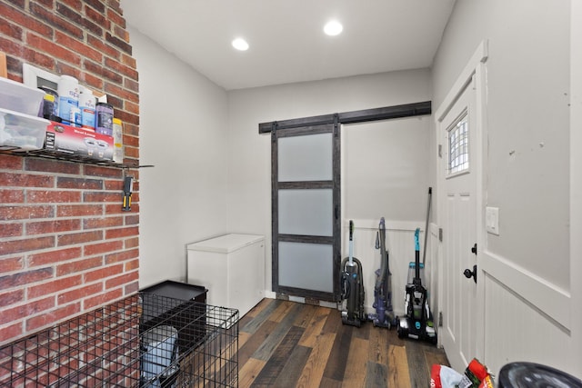 workout area with brick wall, a barn door, and dark hardwood / wood-style floors