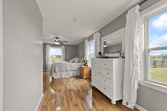 bedroom featuring ceiling fan, hardwood / wood-style flooring, and a textured ceiling