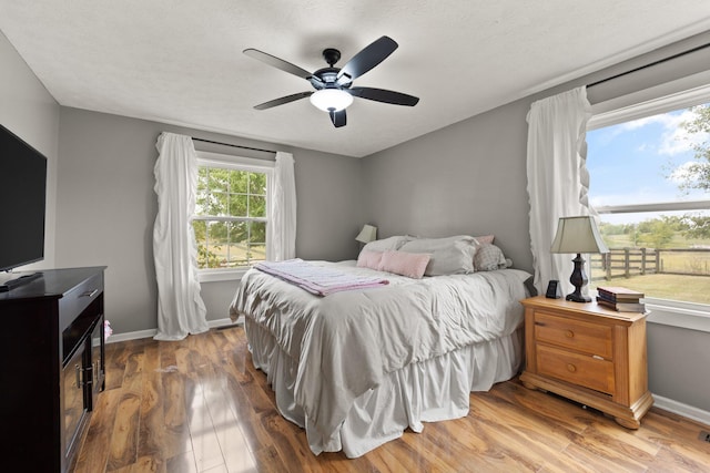 bedroom with ceiling fan, wood-type flooring, and a textured ceiling