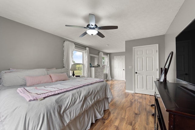 bedroom with a textured ceiling, ceiling fan, and dark hardwood / wood-style floors