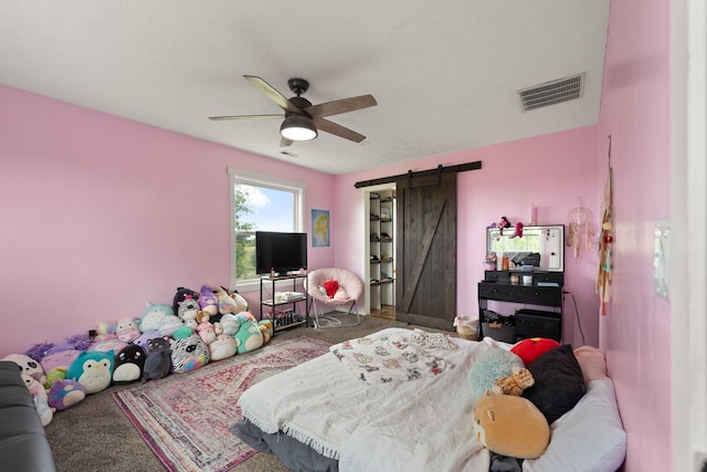 bedroom featuring a barn door, ceiling fan, and carpet flooring