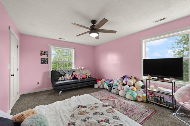 bedroom with a textured ceiling, dark colored carpet, and ceiling fan