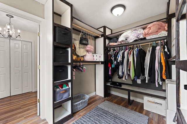 spacious closet with hardwood / wood-style flooring and a notable chandelier