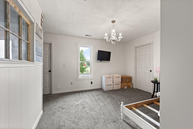 interior space featuring a textured ceiling, a notable chandelier, and carpet floors