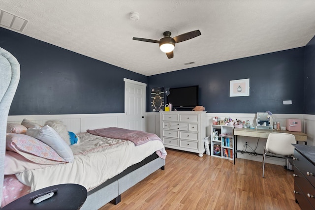 bedroom with a textured ceiling, light hardwood / wood-style flooring, and ceiling fan