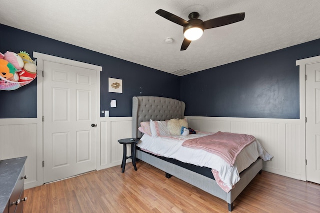 bedroom featuring a textured ceiling, ceiling fan, and light wood-type flooring