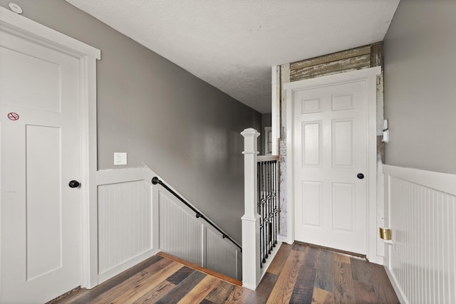 staircase featuring a textured ceiling and wood-type flooring