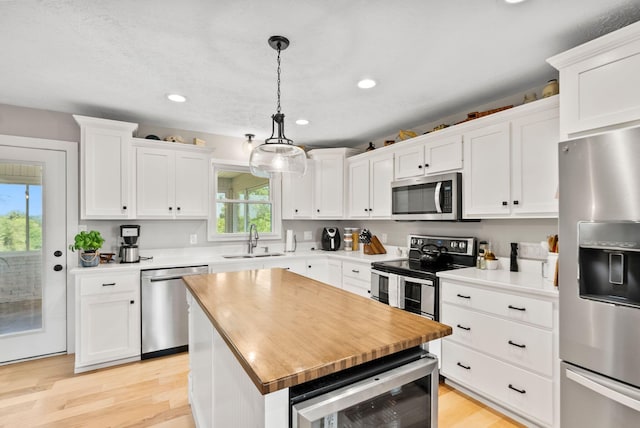 kitchen with white cabinets, a wealth of natural light, appliances with stainless steel finishes, and beverage cooler