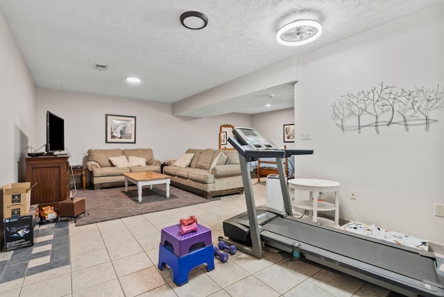 workout room featuring a textured ceiling and light tile patterned floors