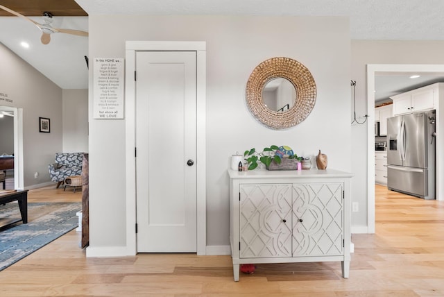 hall featuring light wood-type flooring and a textured ceiling