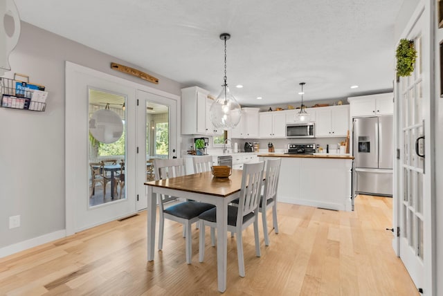 dining space featuring light hardwood / wood-style floors, a textured ceiling, and sink