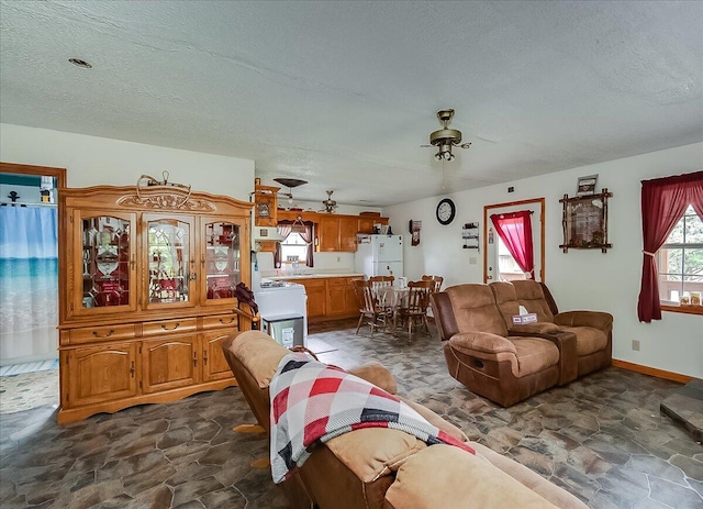 living room featuring ceiling fan and a textured ceiling