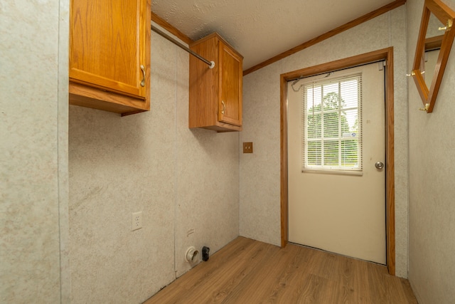 laundry area with cabinets, ornamental molding, a textured ceiling, and light hardwood / wood-style flooring