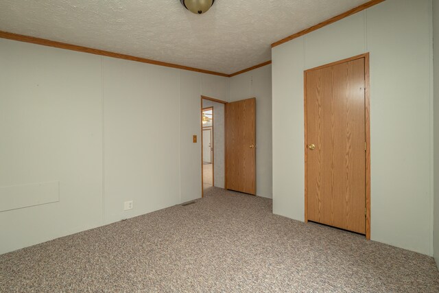 spare room featuring crown molding, a textured ceiling, and light colored carpet