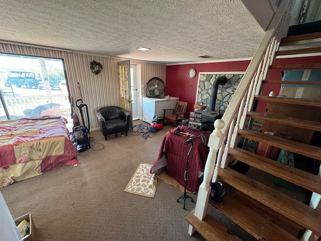 carpeted bedroom with a wood stove, crown molding, and a textured ceiling