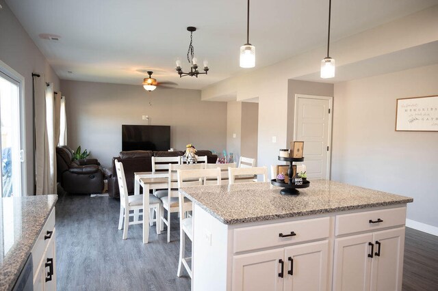 kitchen with dark wood-type flooring, white cabinets, hanging light fixtures, and a kitchen island