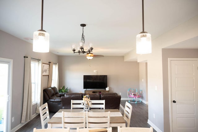 dining room with ceiling fan with notable chandelier, dark wood-type flooring, and a healthy amount of sunlight