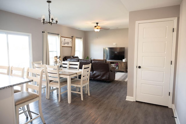 dining space with ceiling fan with notable chandelier and dark hardwood / wood-style flooring