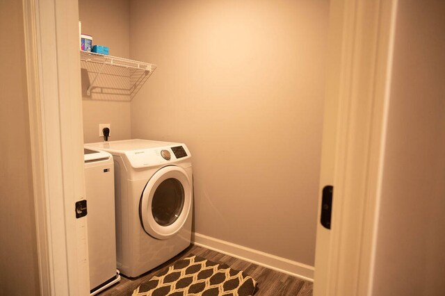 clothes washing area with dark hardwood / wood-style flooring and independent washer and dryer