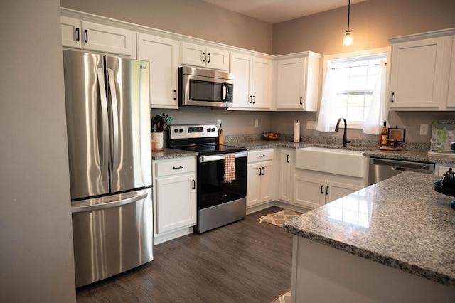 kitchen with stone countertops, dark wood-type flooring, stainless steel appliances, sink, and white cabinets