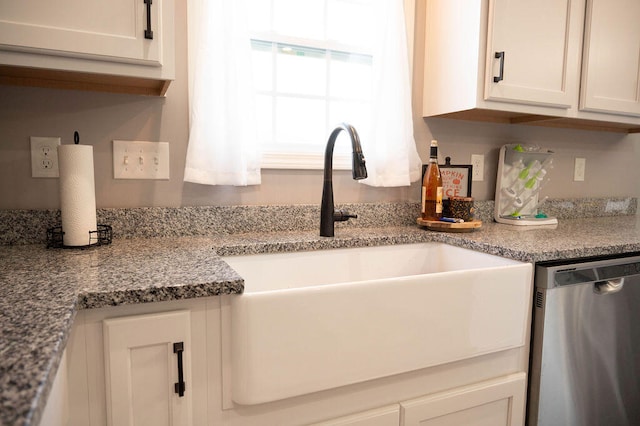 kitchen with light stone countertops, sink, white cabinetry, and stainless steel dishwasher