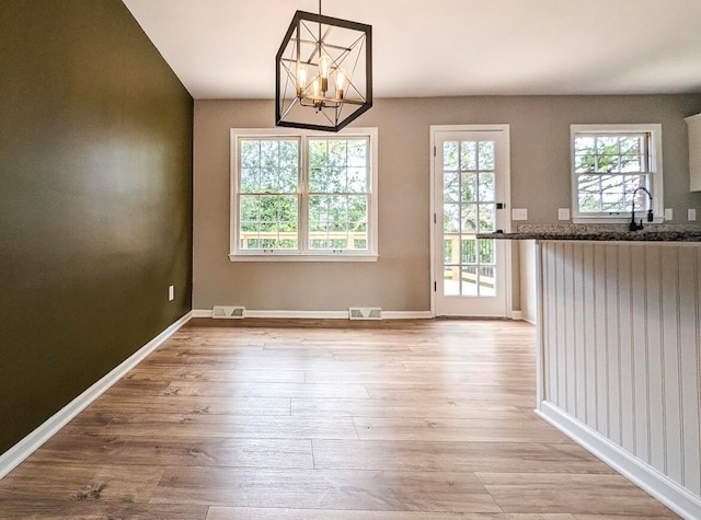 interior space featuring a healthy amount of sunlight, sink, a notable chandelier, and light hardwood / wood-style floors