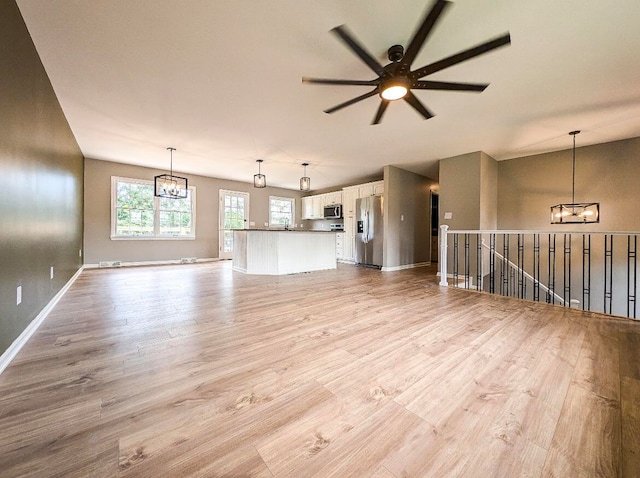 unfurnished living room featuring lofted ceiling, ceiling fan, and light hardwood / wood-style floors