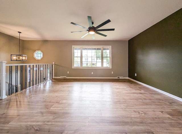 unfurnished room with lofted ceiling, ceiling fan with notable chandelier, and light wood-type flooring