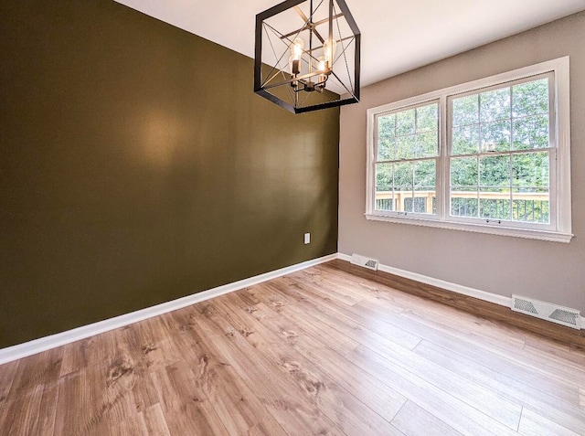 unfurnished room featuring light hardwood / wood-style flooring and an inviting chandelier