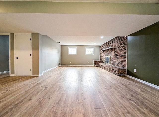 unfurnished living room with light wood-type flooring, a brick fireplace, and brick wall