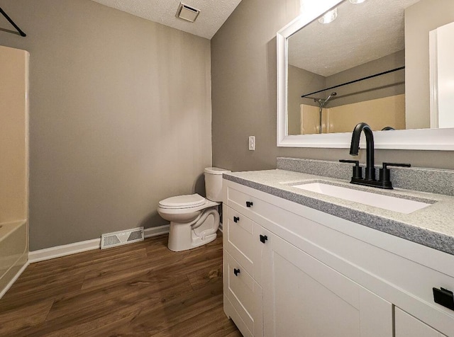 full bathroom featuring a textured ceiling, vanity, shower / washtub combination, toilet, and hardwood / wood-style flooring