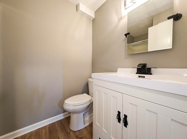 bathroom featuring toilet, hardwood / wood-style flooring, a textured ceiling, and vanity