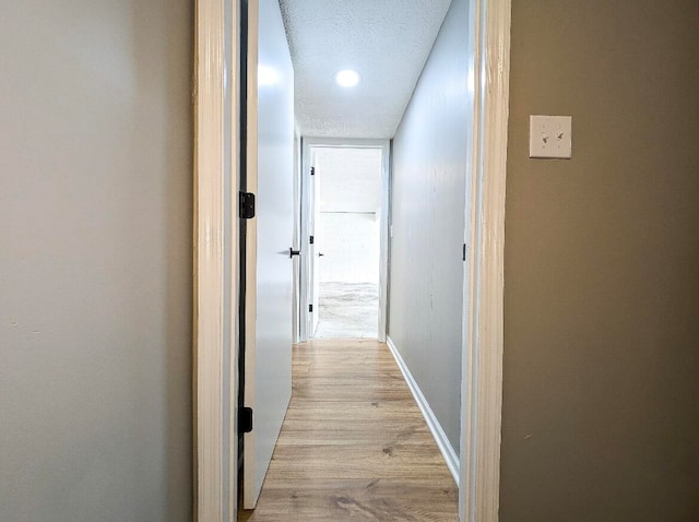 hall featuring light wood-type flooring and a textured ceiling