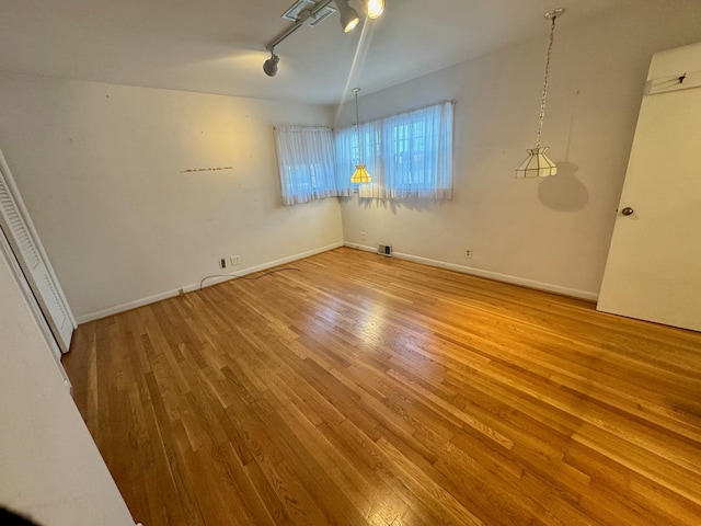 spare room featuring track lighting and wood-type flooring