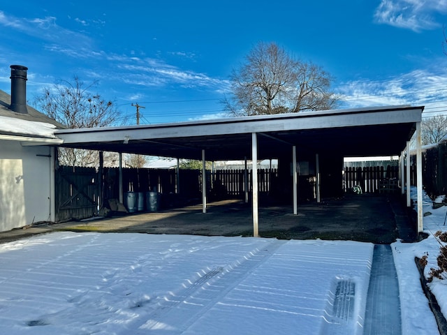 snow covered parking area featuring a carport