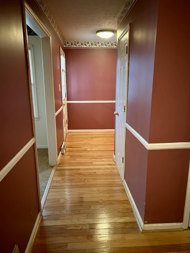 hallway with light wood-style flooring and baseboards