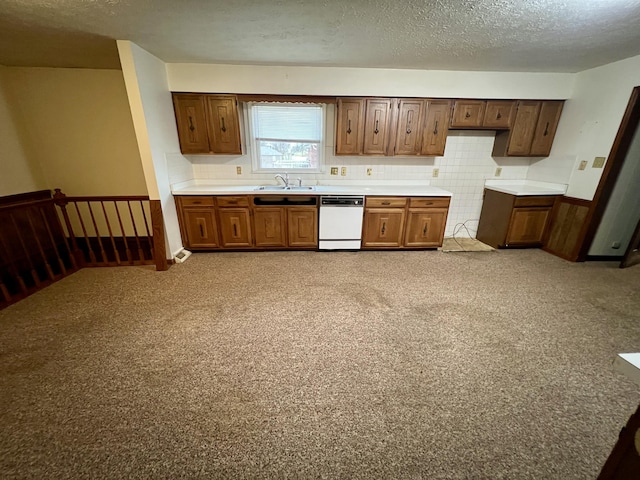 kitchen with a sink, a textured ceiling, white dishwasher, and light countertops