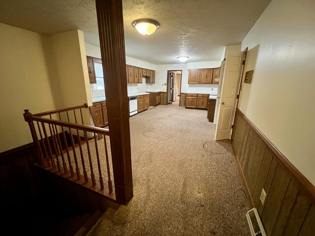 interior space with light carpet, visible vents, wainscoting, and a textured ceiling