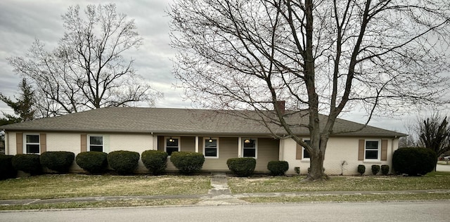 single story home featuring brick siding, a chimney, a front yard, and roof with shingles