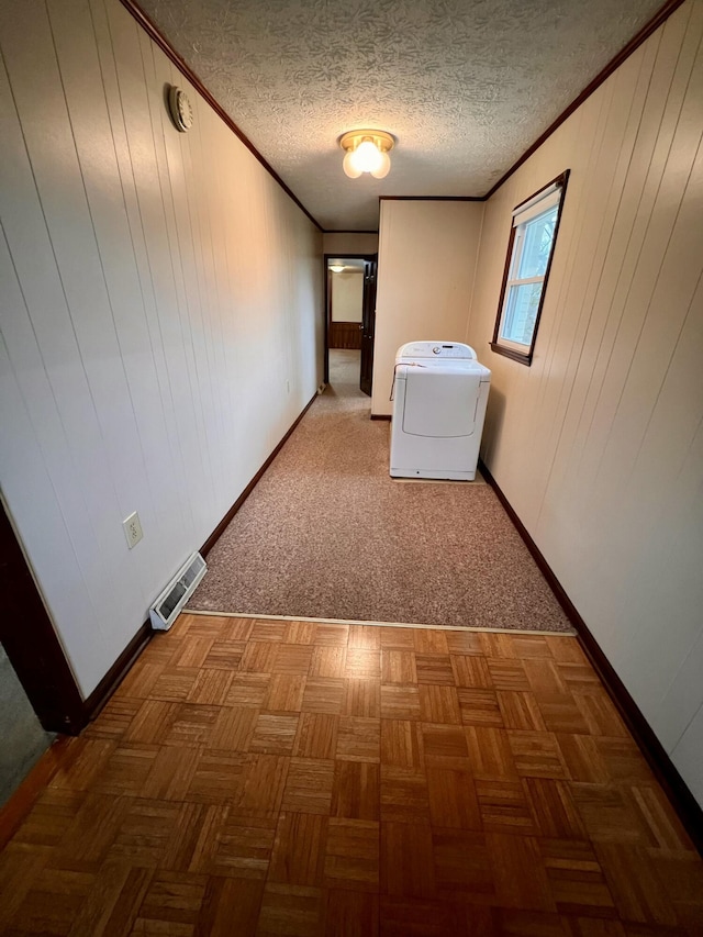 hall featuring visible vents, baseboards, ornamental molding, washer / dryer, and a textured ceiling