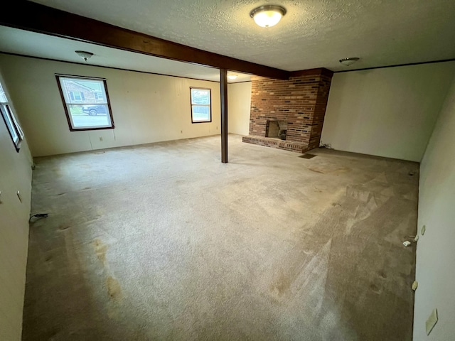 basement featuring a brick fireplace, plenty of natural light, a textured ceiling, and carpet floors